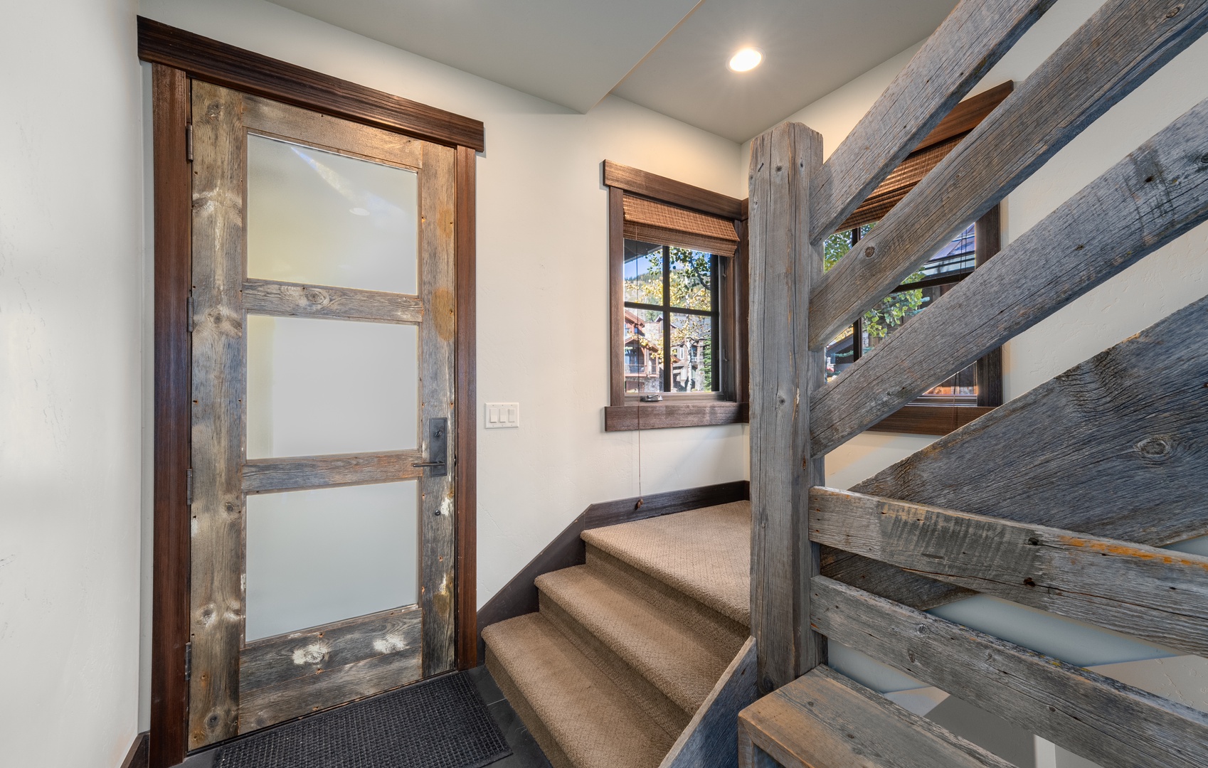 Step into rustic elegance with reclaimed wood beams framing your way upstairs, where natural light and mountain charm greet you at every turn.