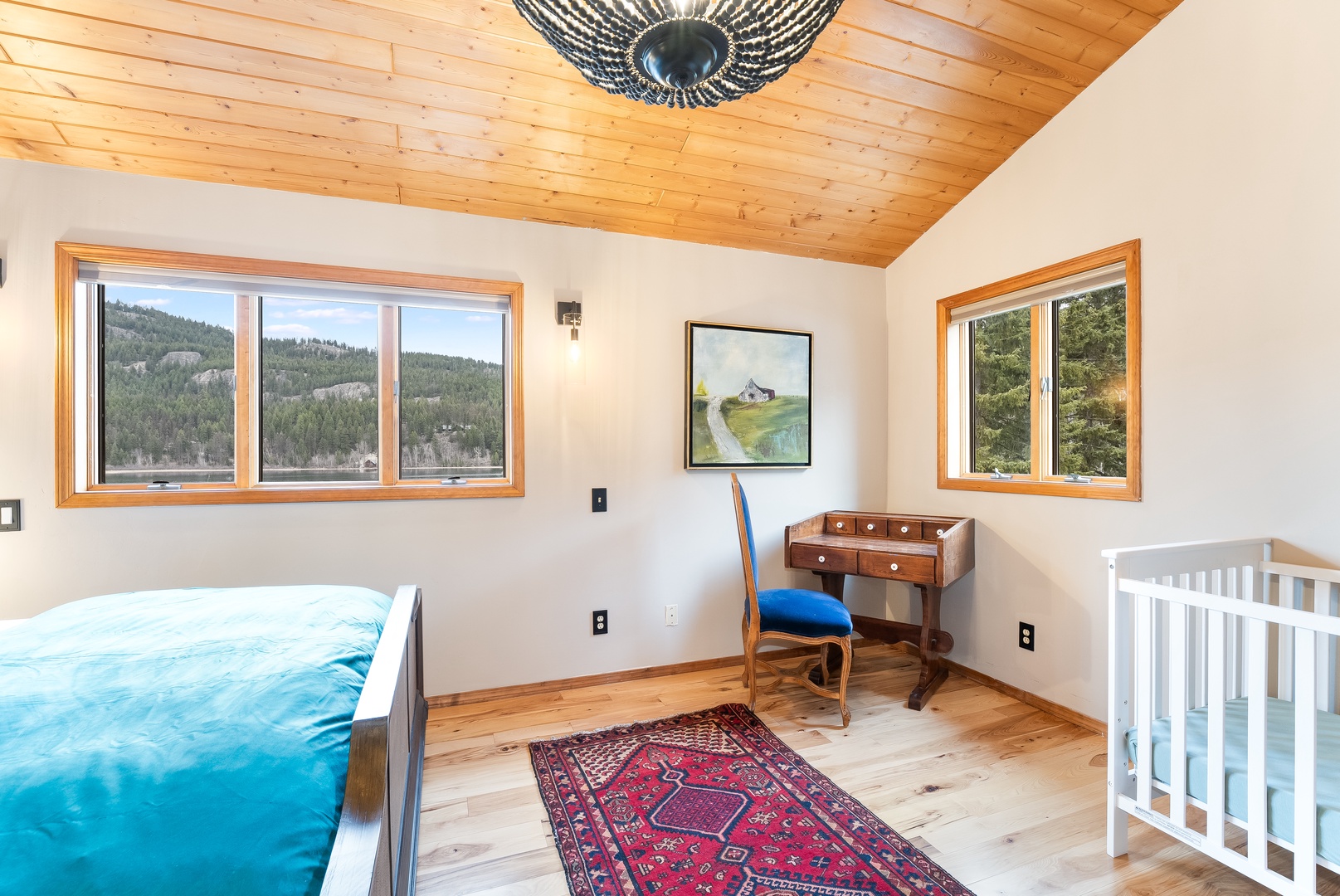 Unwind in your serene bedroom with stunning forest views through expansive windows and warm wood ceiling.