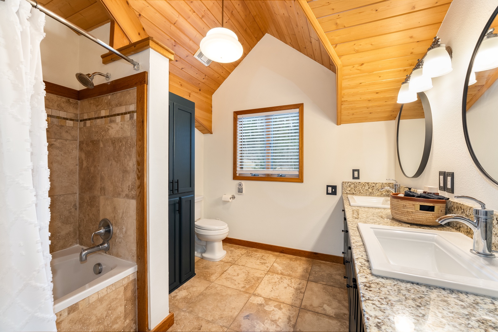 Unwind in your spacious bathroom with granite countertops, dual sinks, and a relaxing tub-shower combo under rustic wood beams.