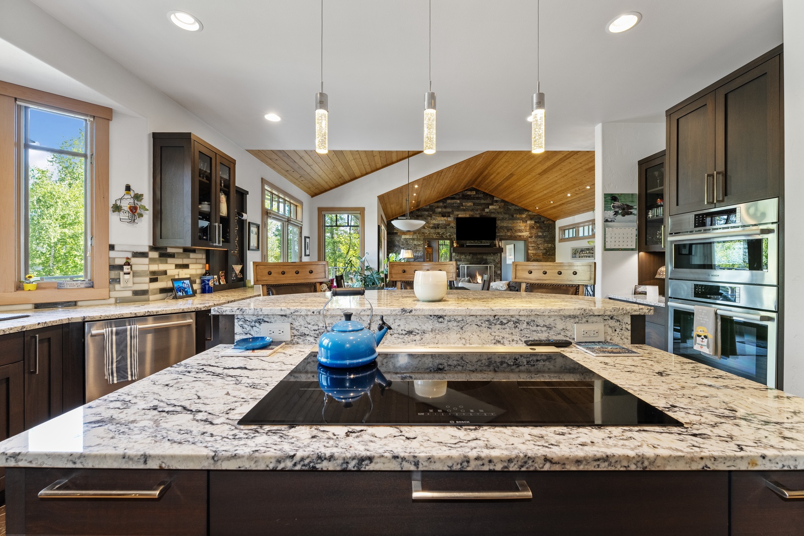 Stunning gourmet kitchen with granite counters and premium appliances, flooded with natural light and views of lush greenery—perfect for memorable vacation meals and gatherings.