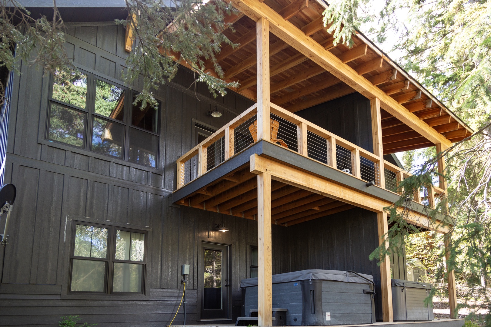 A striking mountain home with natural wood beams, dual outdoor decks, and a private hot tub nestled among towering evergreens—your perfect alpine escape.