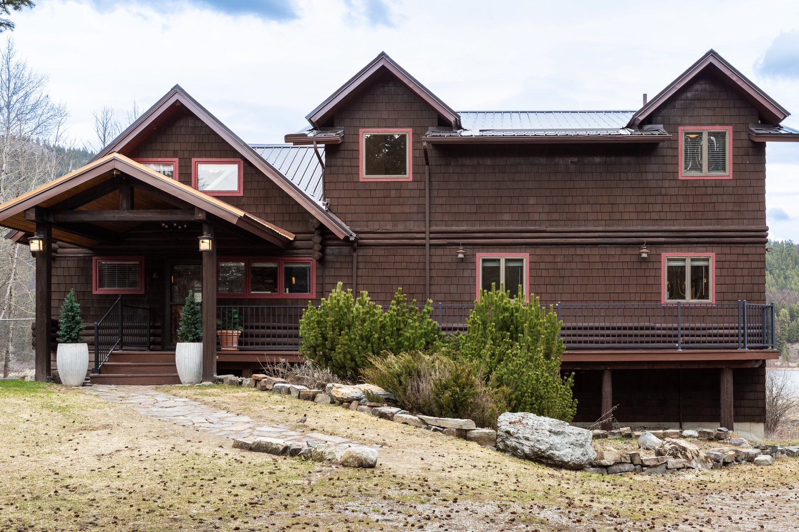 Mountain retreat with rustic charm and natural stone landscaping nestled among towering trees.