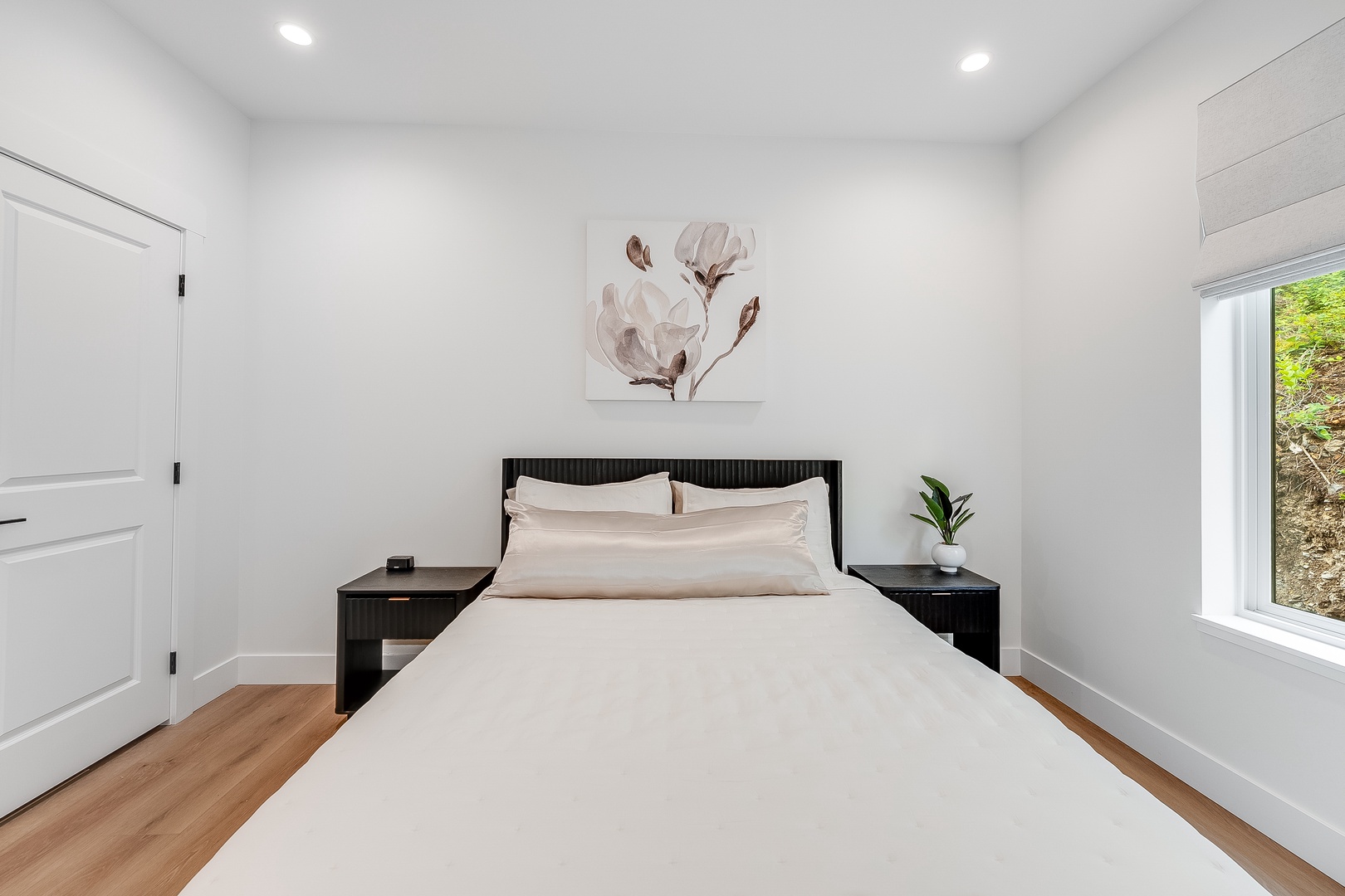 Your serene bedroom awaits with crisp linens, natural light streaming through the window, and peaceful artwork setting the tone for restful nights and refreshed mornings.