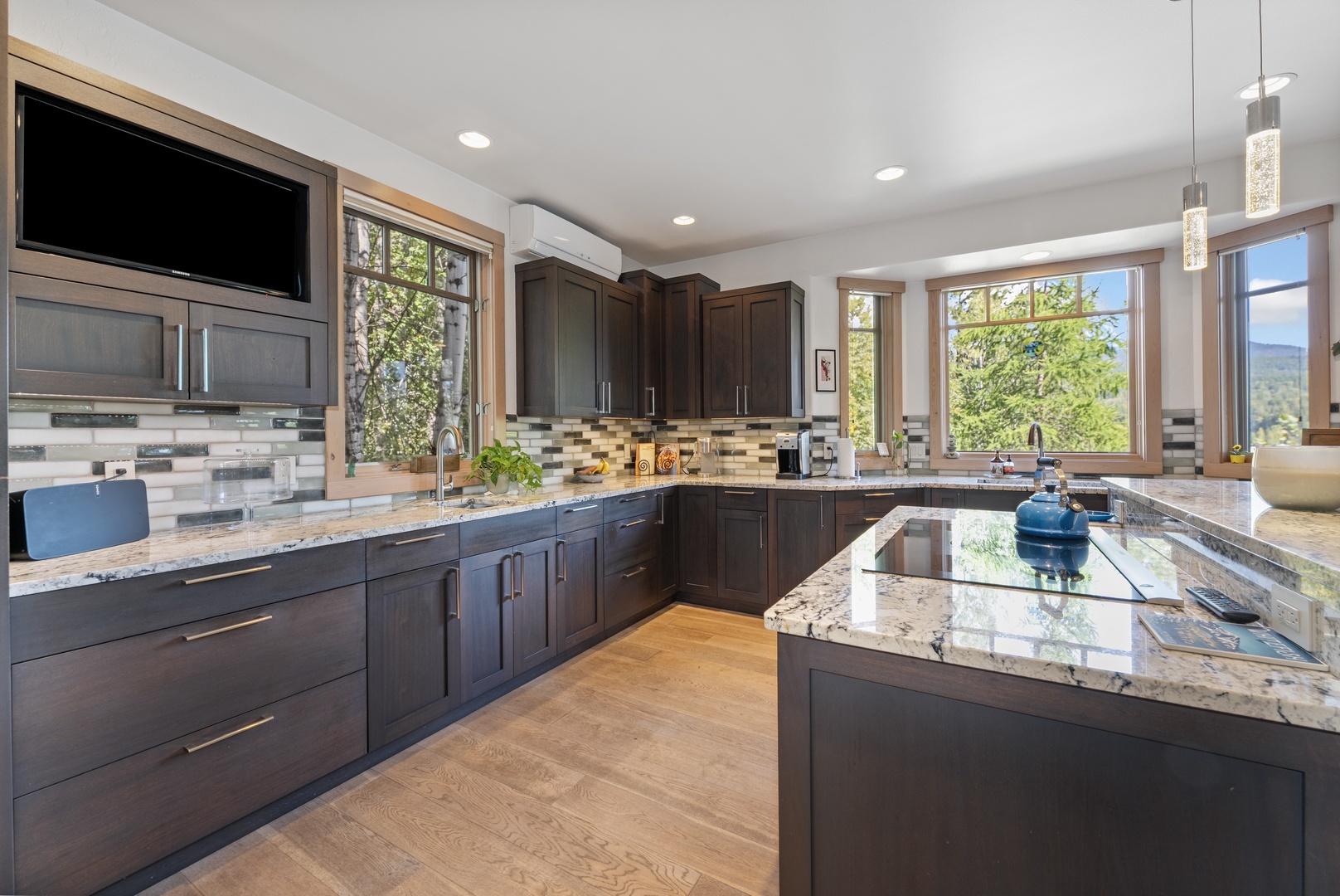 Your gourmet kitchen features stunning granite counters, modern dark cabinetry, and large windows framing peaceful mountain views—perfect for preparing meals while soaking in the scenery.