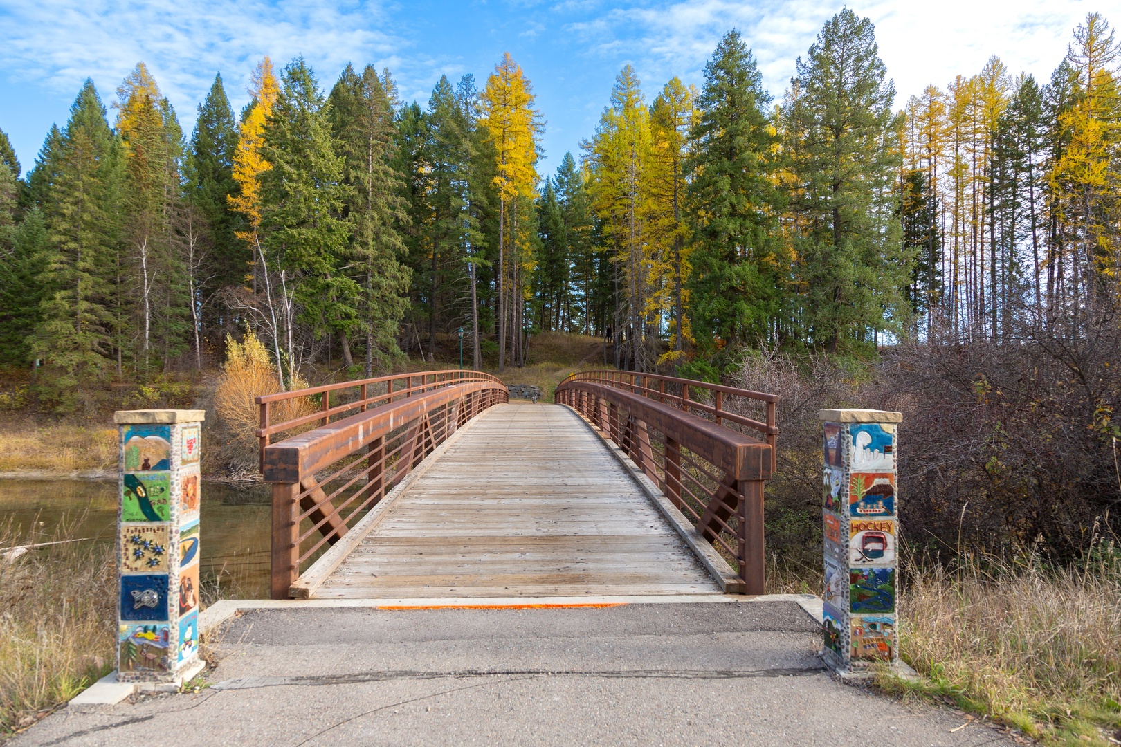 Scenic wooden footbridge surrounded by golden autumn forest creates a peaceful walking path through natural landscape near the property.