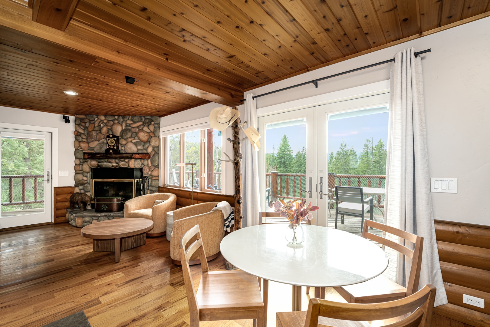 Relax in your cozy living space with vaulted wood ceilings, a stone fireplace, and dining area opening to a private deck with forest views.