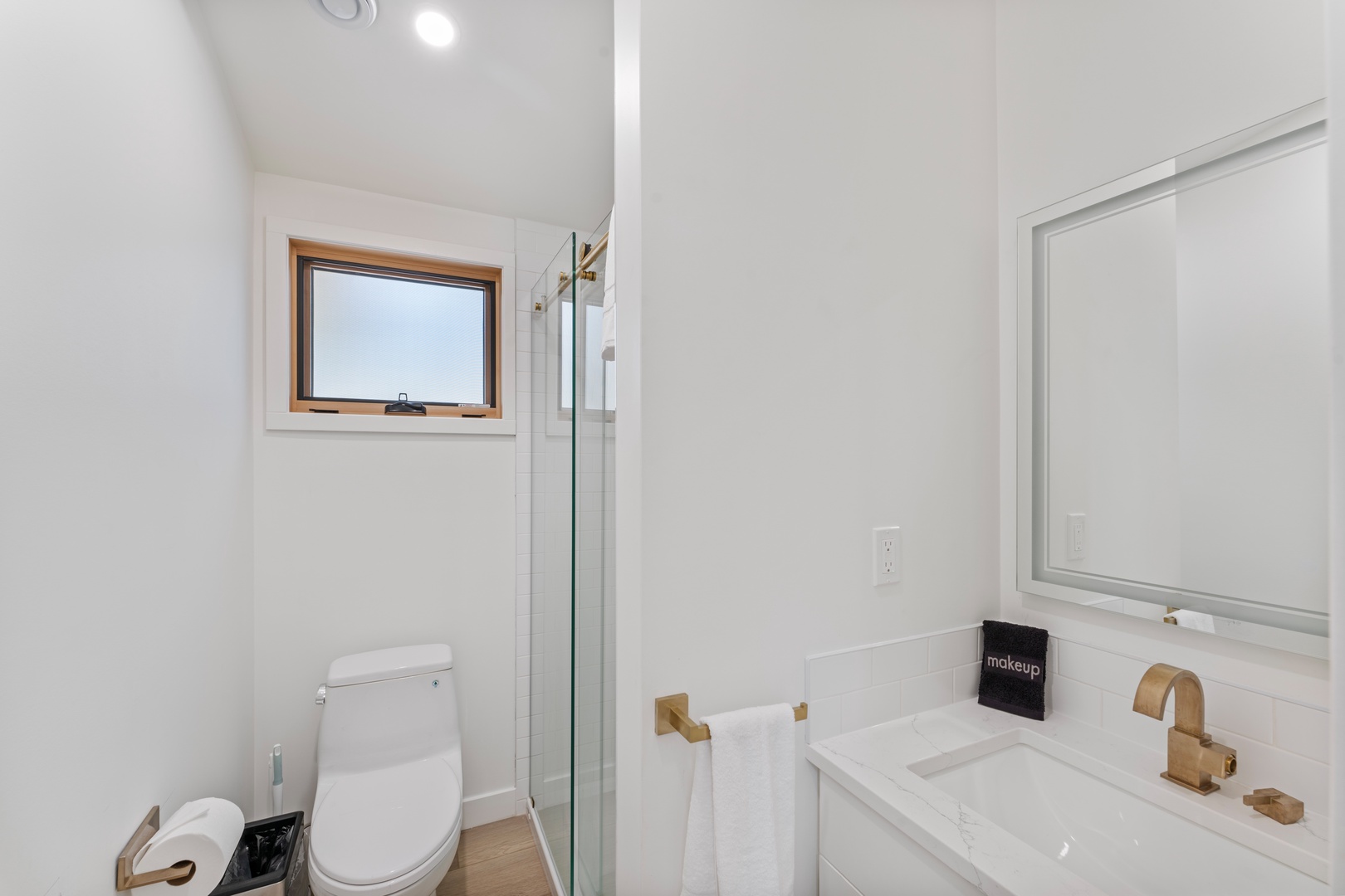 Step into your pristine bathroom featuring a spacious walk-in shower, elegant marble vanity, and warm gold fixtures for a luxurious refresh.