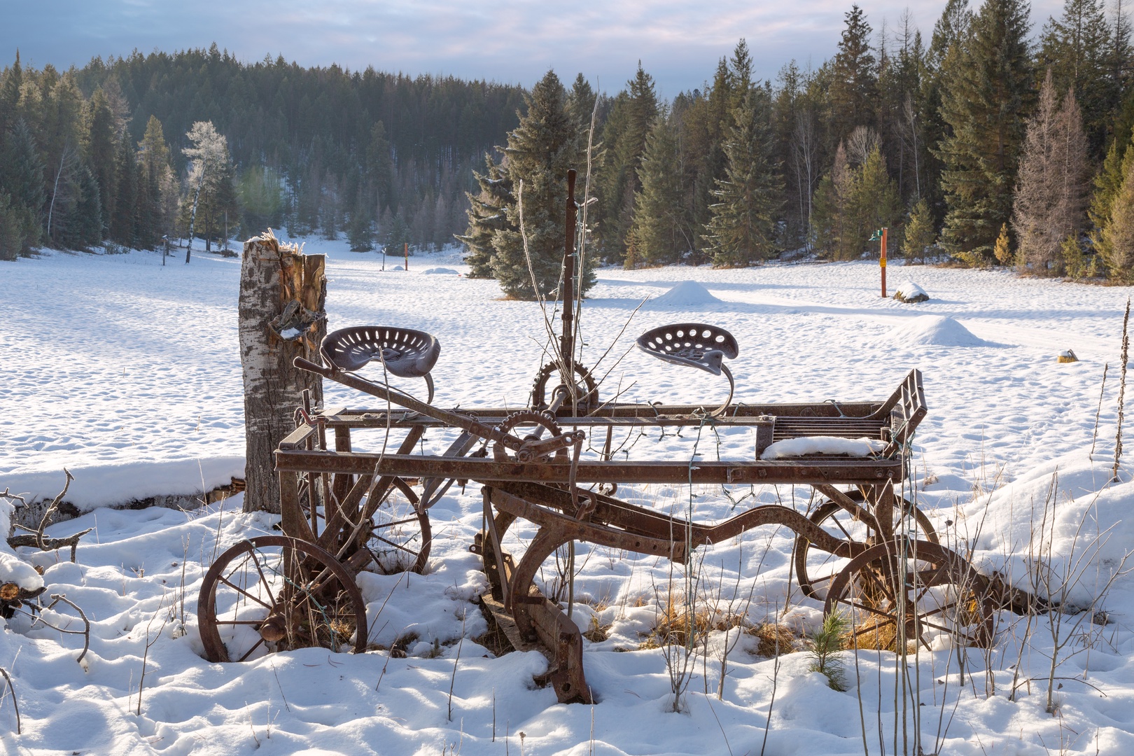 Pristine winter landscape surrounds the property with snow-covered forests and charming vintage farm equipment creating a picturesque countryside setting.
