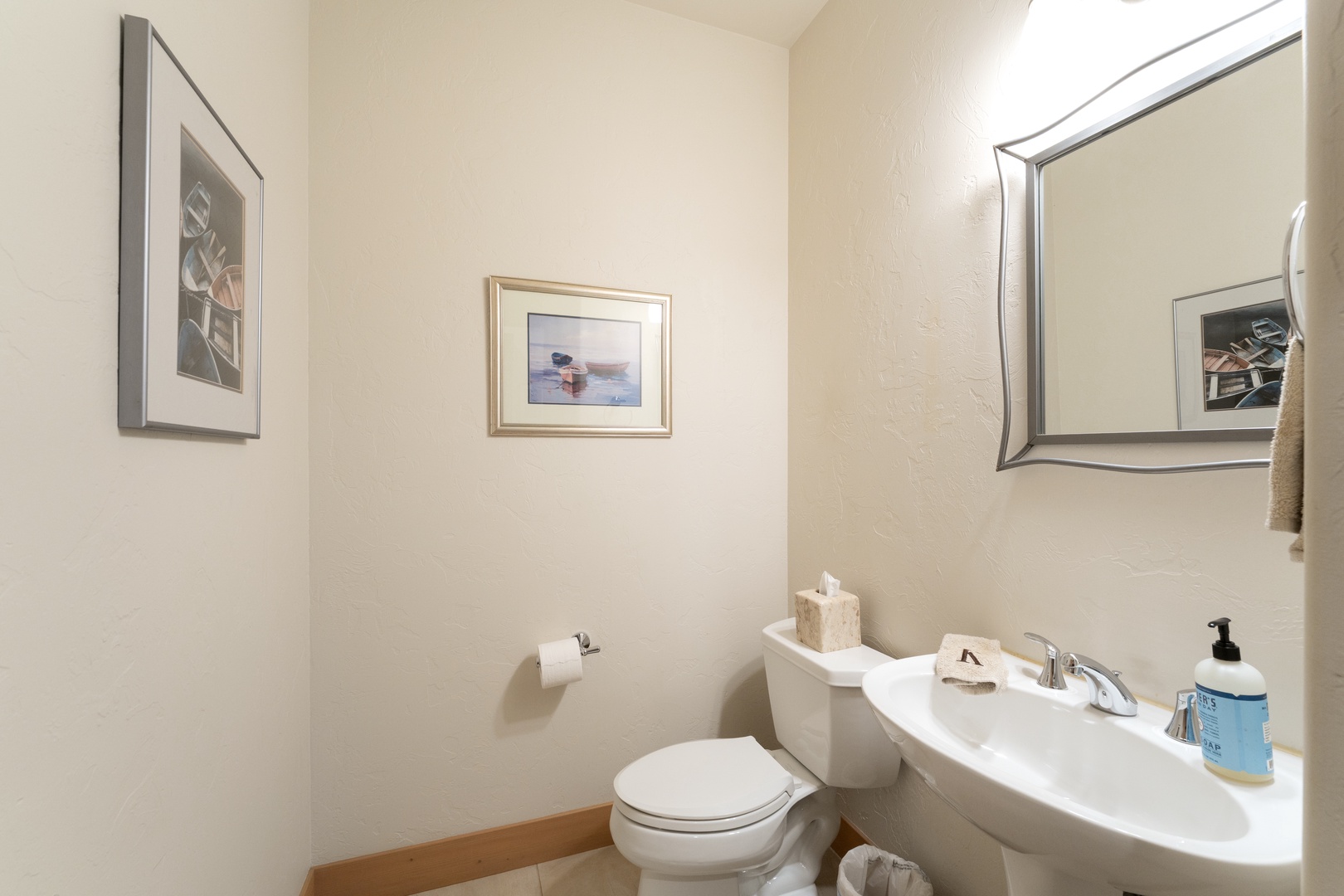A bright, welcoming powder room awaits you, with clean lines and thoughtful touches like fresh towels and coastal artwork to help you feel right at home.