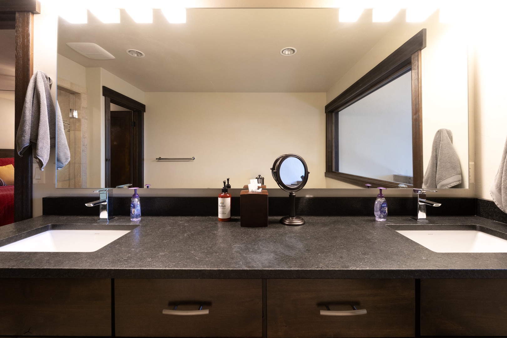 Freshen up in style at your dual-sink vanity, where sleek dark counters meet ample storage and thoughtful touches like a lighted mirror and fresh towels await.