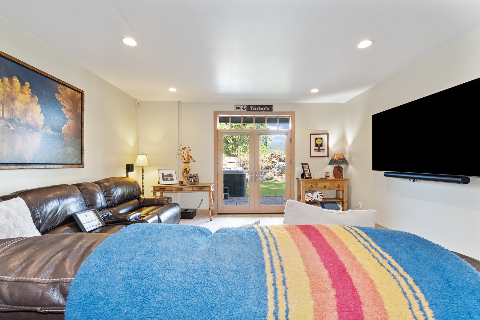 Sink into the plush leather sofa and unwind in your welcoming living space, where natural light flows through glass doors and a vibrant rug adds warmth underfoot.