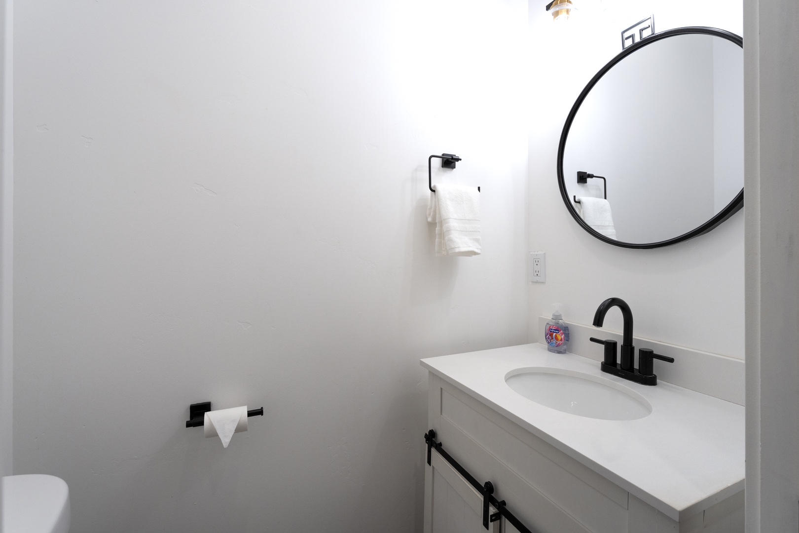 Your private bathroom features a sleek vanity with modern black fixtures and a stylish round mirror for your daily routine.