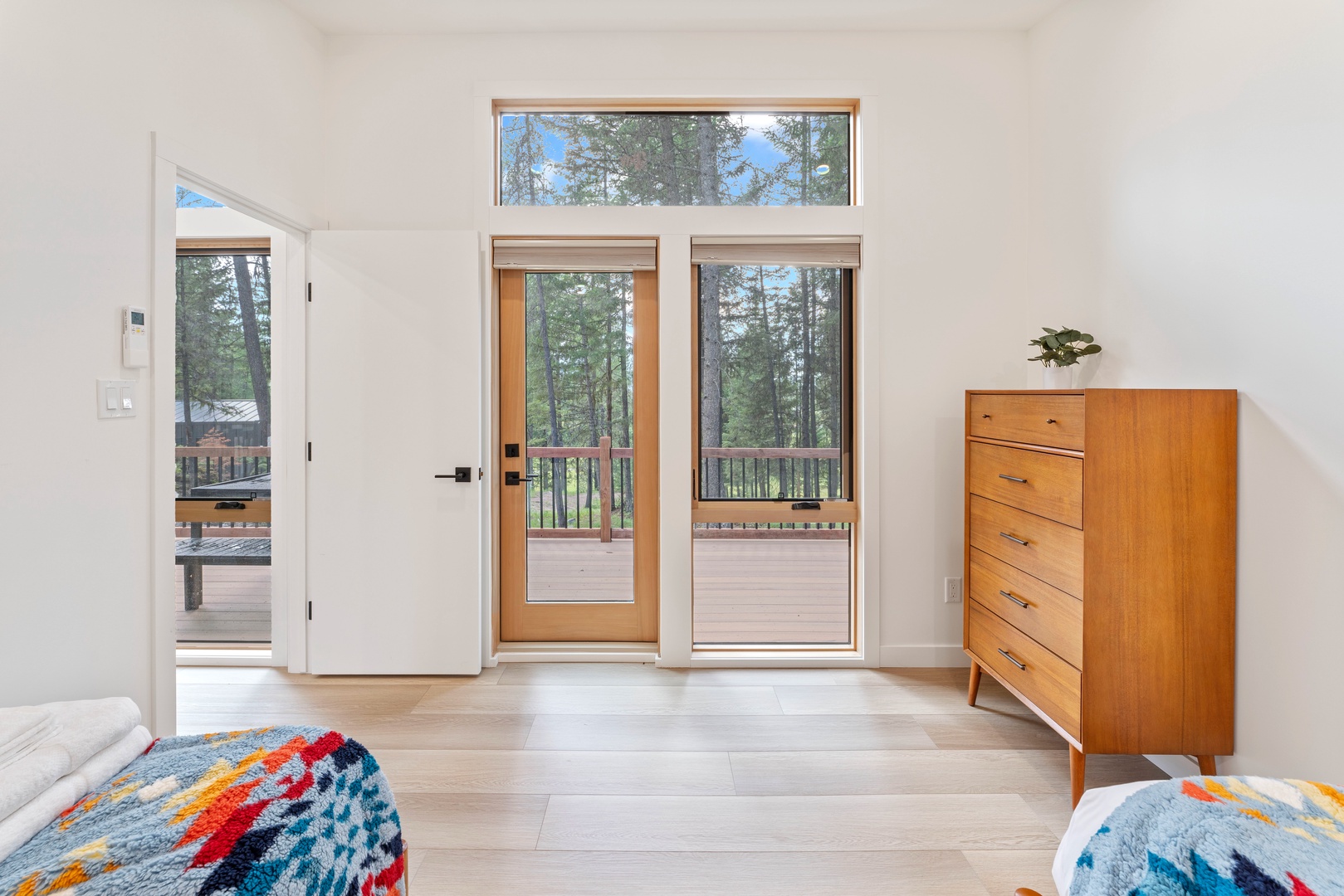 Step into your bright bedroom where forest views greet you through floor-to-ceiling windows and your private balcony awaits morning coffee.