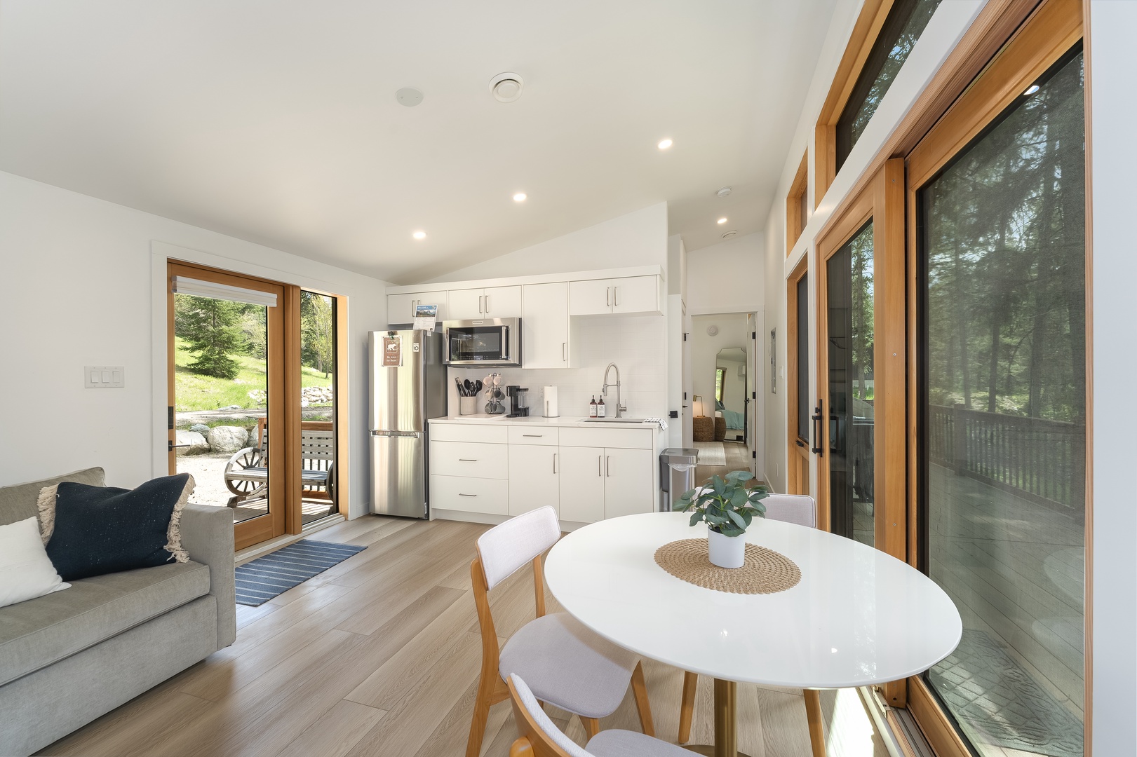 Sunlit open-concept living with a fully equipped kitchen and dining space for your meals. Step outside to your private deck and enjoy the peaceful forest setting.