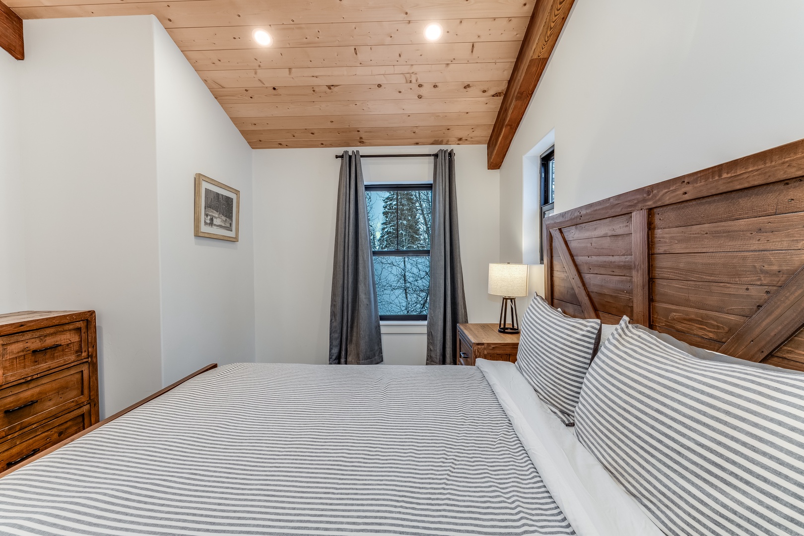 Drift off to sleep in your cozy bedroom featuring rustic wood accents, soft linens, and peaceful forest views through the window.