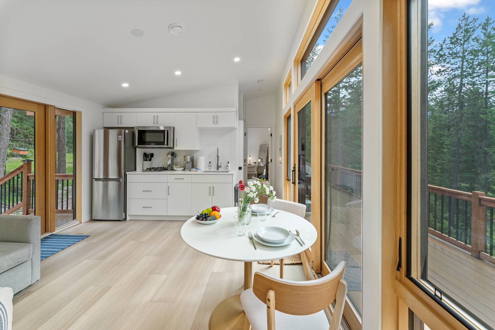 Sunlight fills your open-plan retreat where floor-to-ceiling windows frame lush forest views. Gather at the inviting dining table or step onto your private balcony to breathe in the fresh air.
