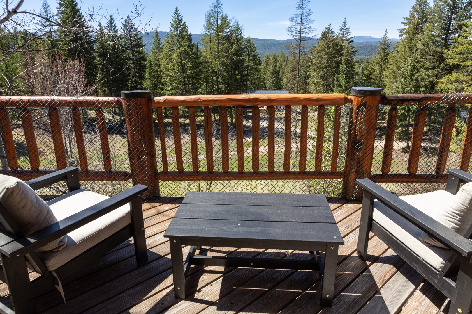 Panoramic forested mountains and rolling hills frame the property's expansive deck, offering a peaceful retreat surrounded by nature.