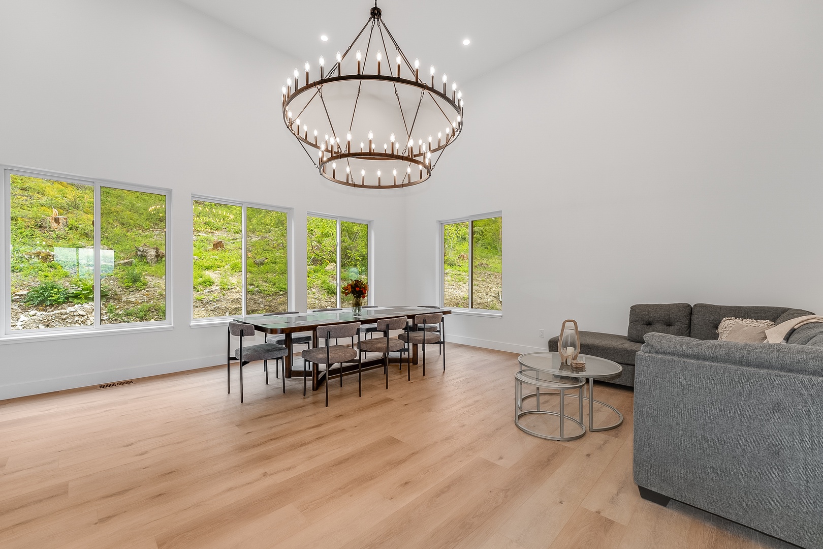 Settle into this spacious open living and dining area, where natural light pours through expansive windows and warm wood floors invite you to unwind in modern comfort.