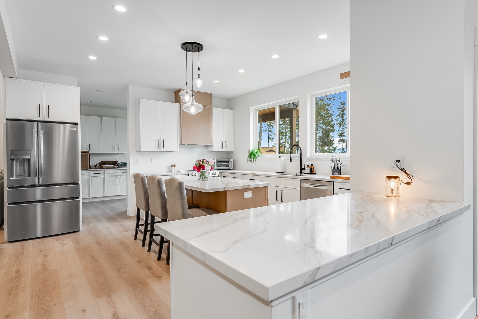 You'll love preparing meals in this bright, modern kitchen with its sleek marble countertops, stainless steel appliances, and spacious island seating. Natural light fills the room, offering serene lakeside views while you cook.