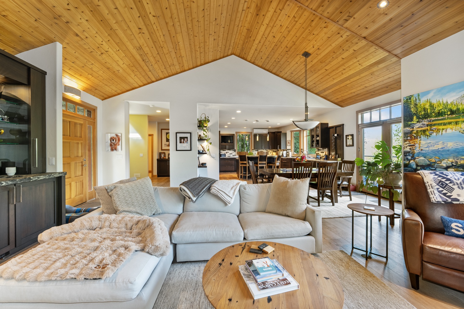 Sink into plush seating beneath soaring wood ceilings that warm the entire open-concept space. Your living area flows seamlessly into the kitchen and dining zones, inviting you to relax and connect.
