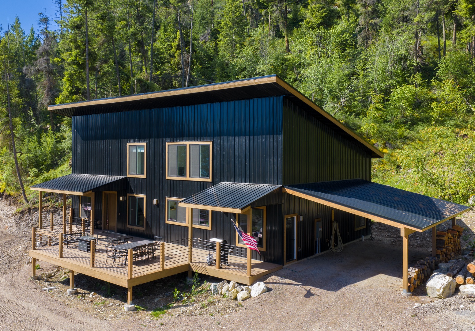 A modern mountain retreat with dark metal siding and warm wood accents, nestled among towering pines, offers peaceful seclusion and easy access to outdoor adventures.