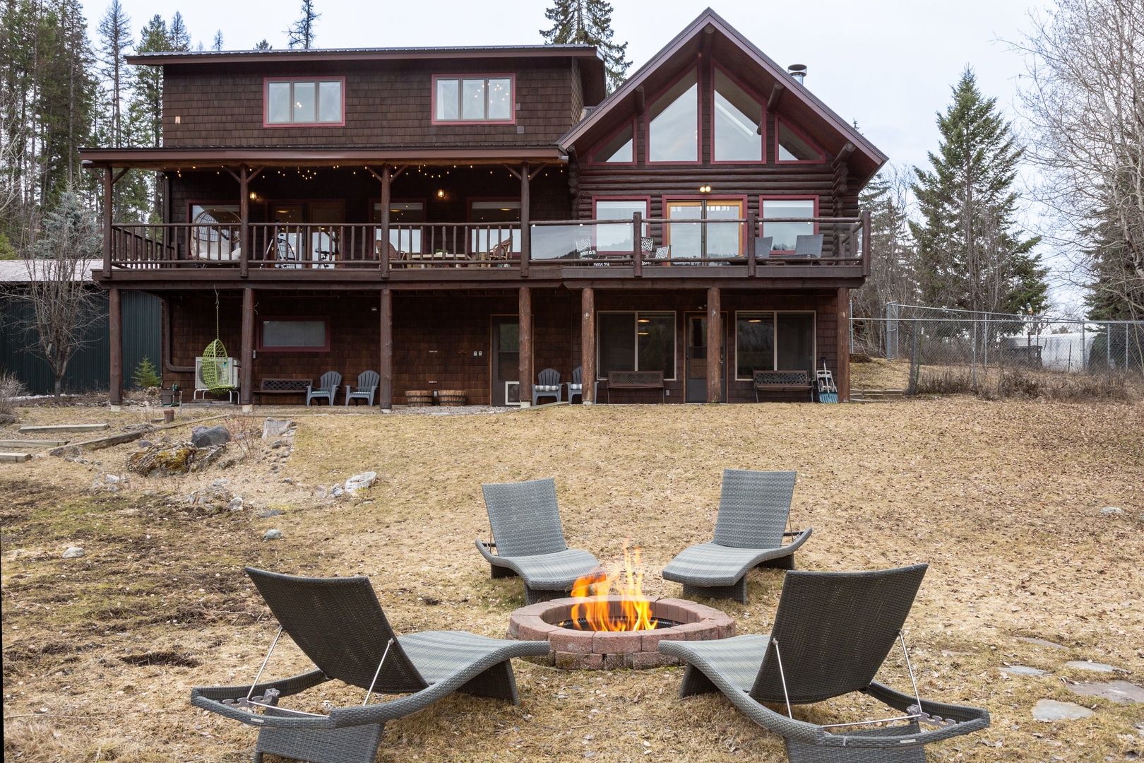 A spacious lodge featuring cozy outdoor fire pit surrounded by comfortable seating, perfect for evening gatherings under the trees.