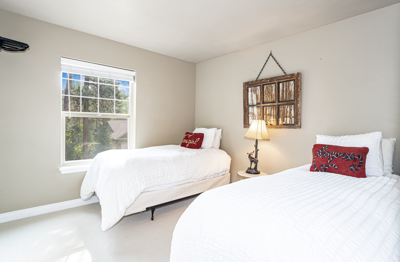 Unwind in your serene bedroom featuring two plush beds dressed in crisp linens and colorful accent pillows. Natural light pours through the window, highlighting charming rustic décor that makes this space feel like your personal retreat.