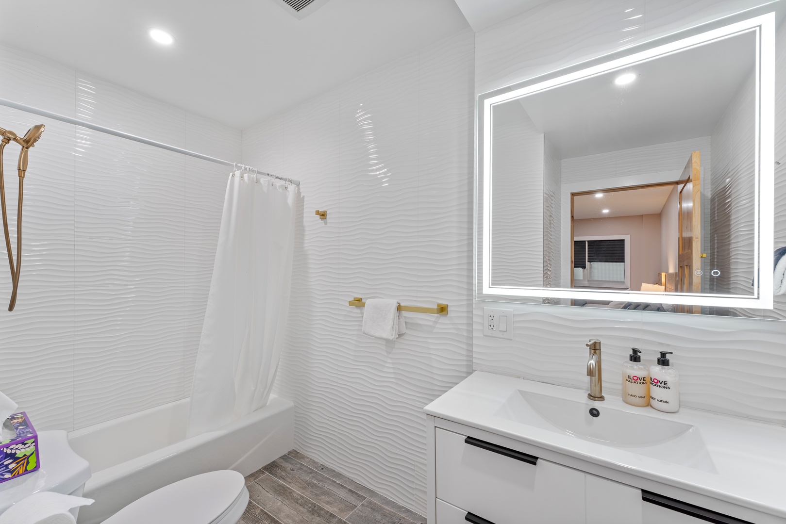 You'll love the sleek, modern bathroom with its textured white tiles, bright lighting, and a tub-shower combo perfect for unwinding after your adventures.