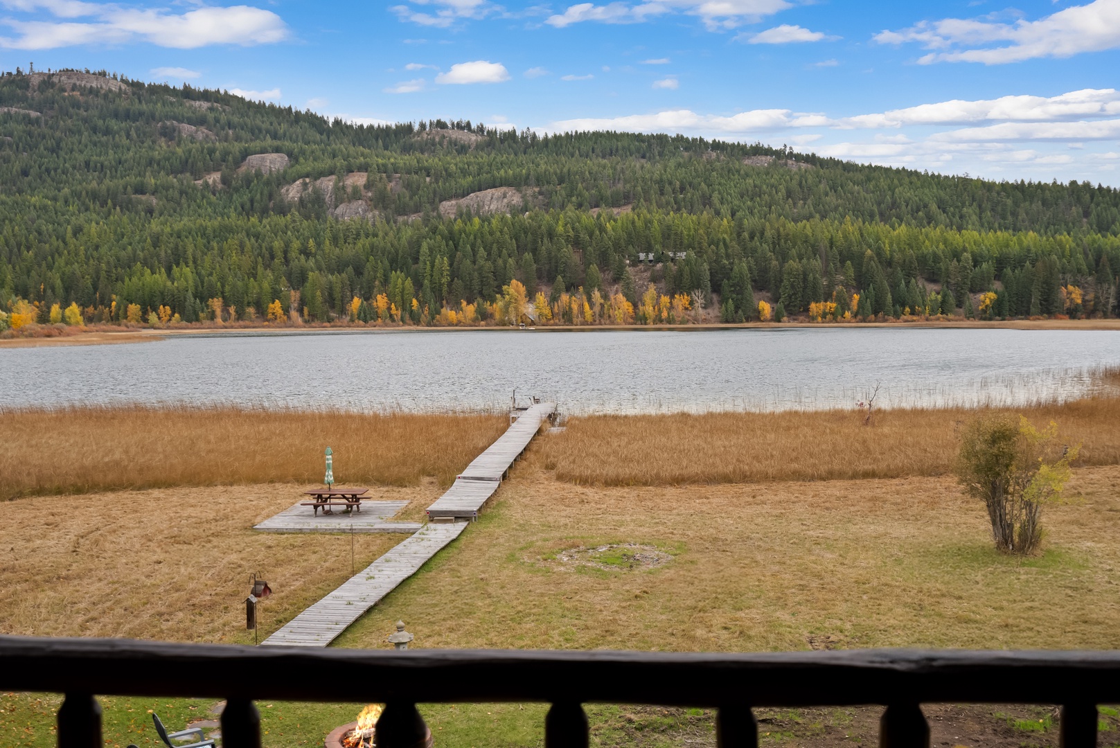 Stunning lakefront views with private dock access surrounded by forest-covered mountains and vibrant autumn colors.