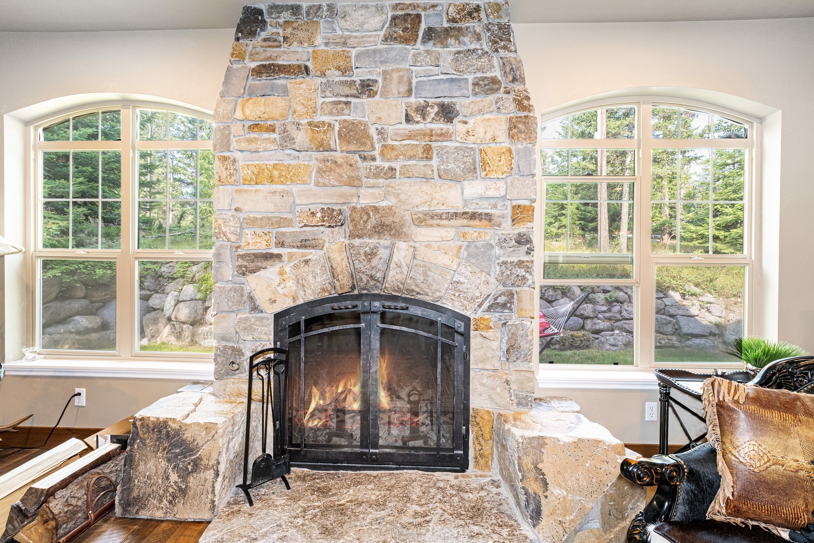 Cozy up by your own stone fireplace framed by arched windows overlooking the peaceful wooded surroundings—perfect for relaxing mornings and quiet evenings.
