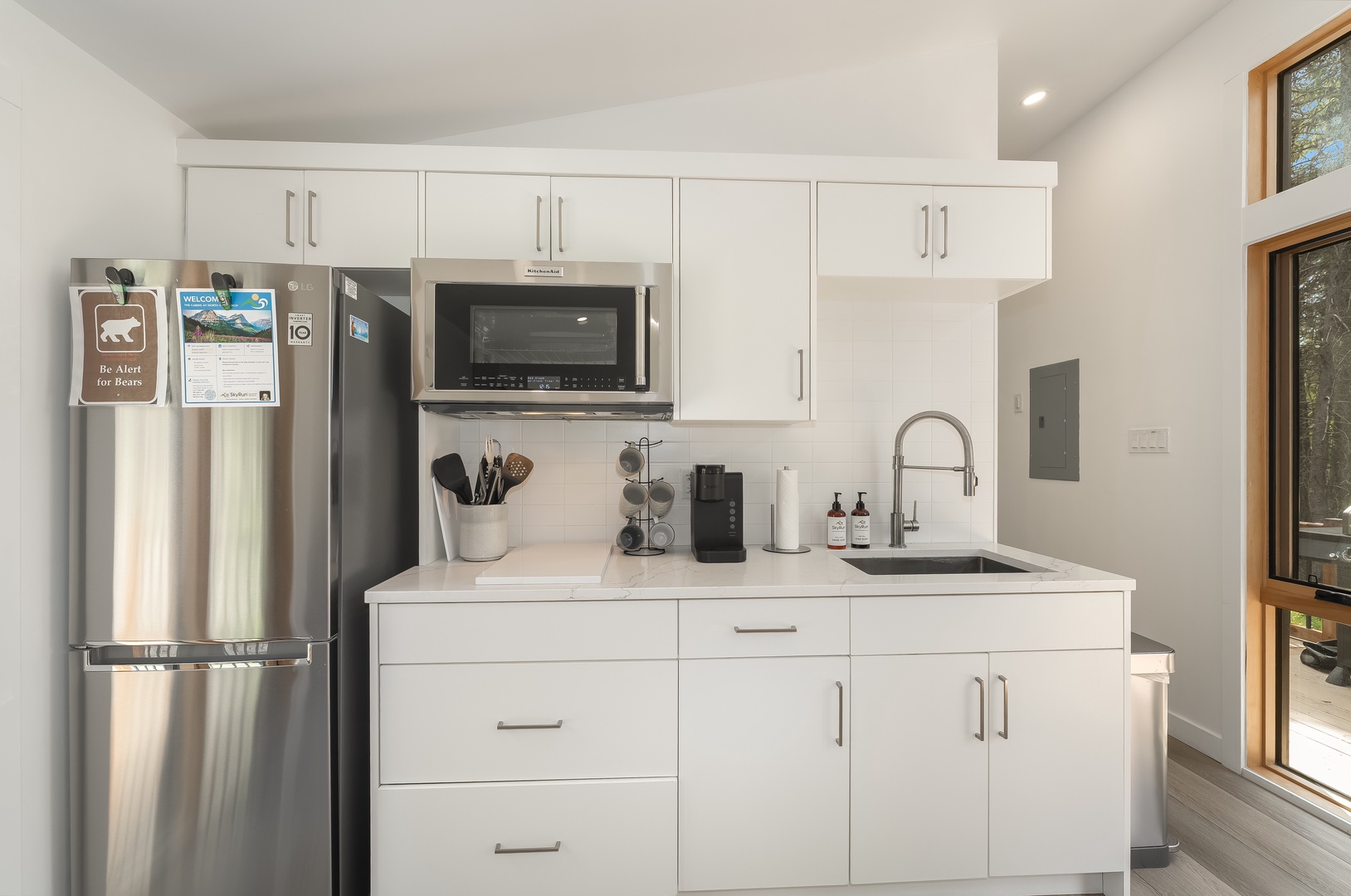 Your fully equipped kitchen offers everything you need for effortless meal prep, from the stainless-steel fridge to the microwave and coffee maker, all bathed in natural light from large windows.