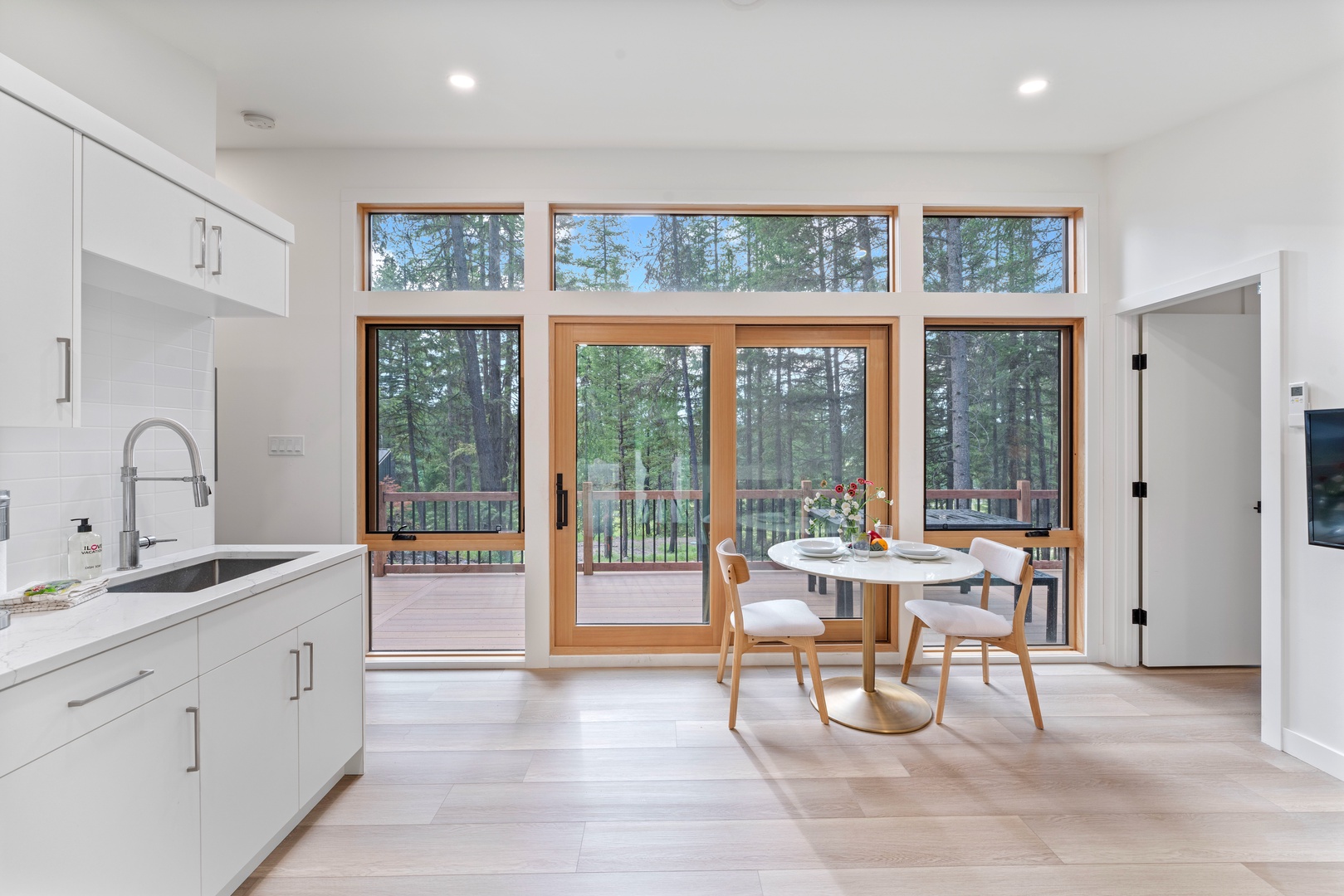 Prepare meals in your modern kitchen while enjoying stunning forest views through floor-to-ceiling windows that fill the space with natural light.