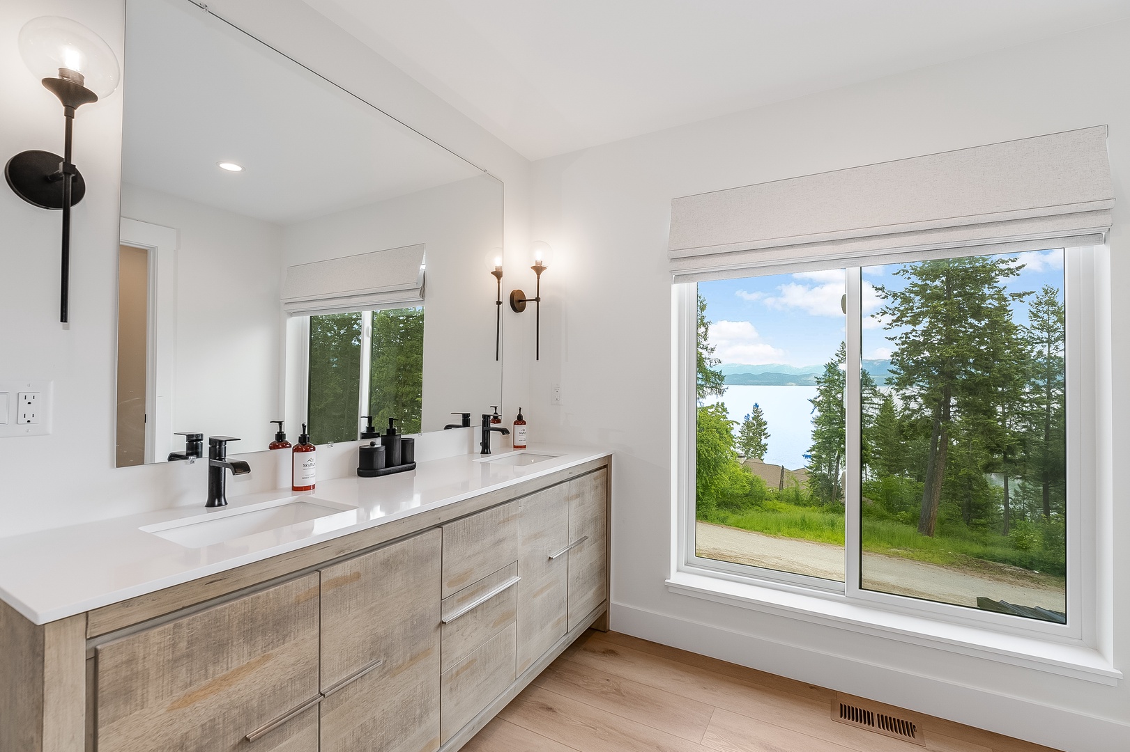 Bright, modern bathroom with dual vanity and stunning lake views. Refresh in this serene space where natural light floods through large windows overlooking peaceful waters.
