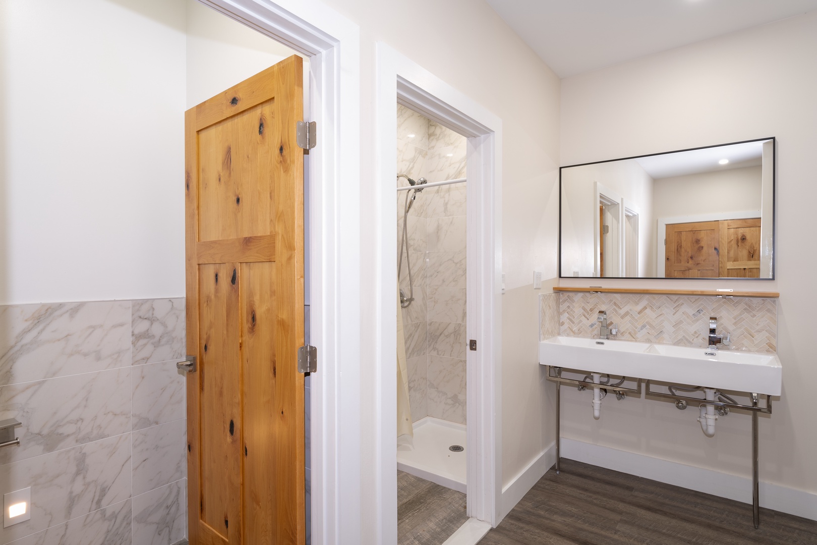 Light-filled bathroom with herringbone-tiled vanity, sleek double sinks, and walk-in shower—where your mornings start refreshed and ready for adventure.
