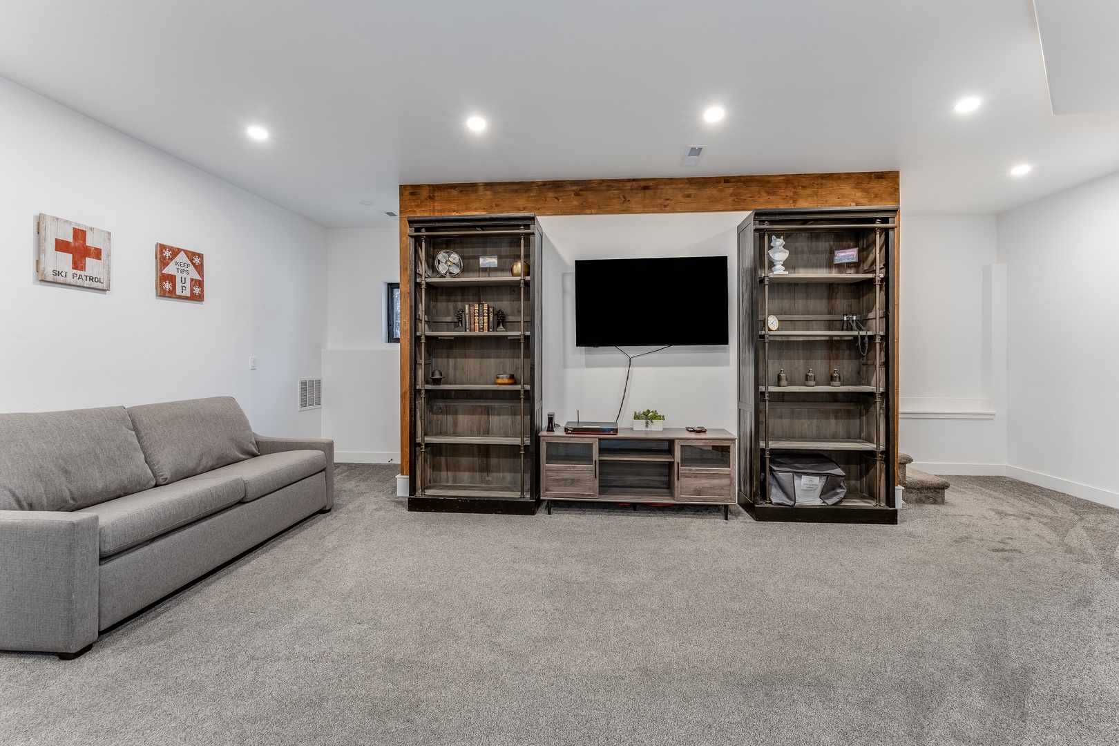 Unwind in your spacious basement lounge with plush seating, entertainment center, and stylish industrial shelving for all your belongings.