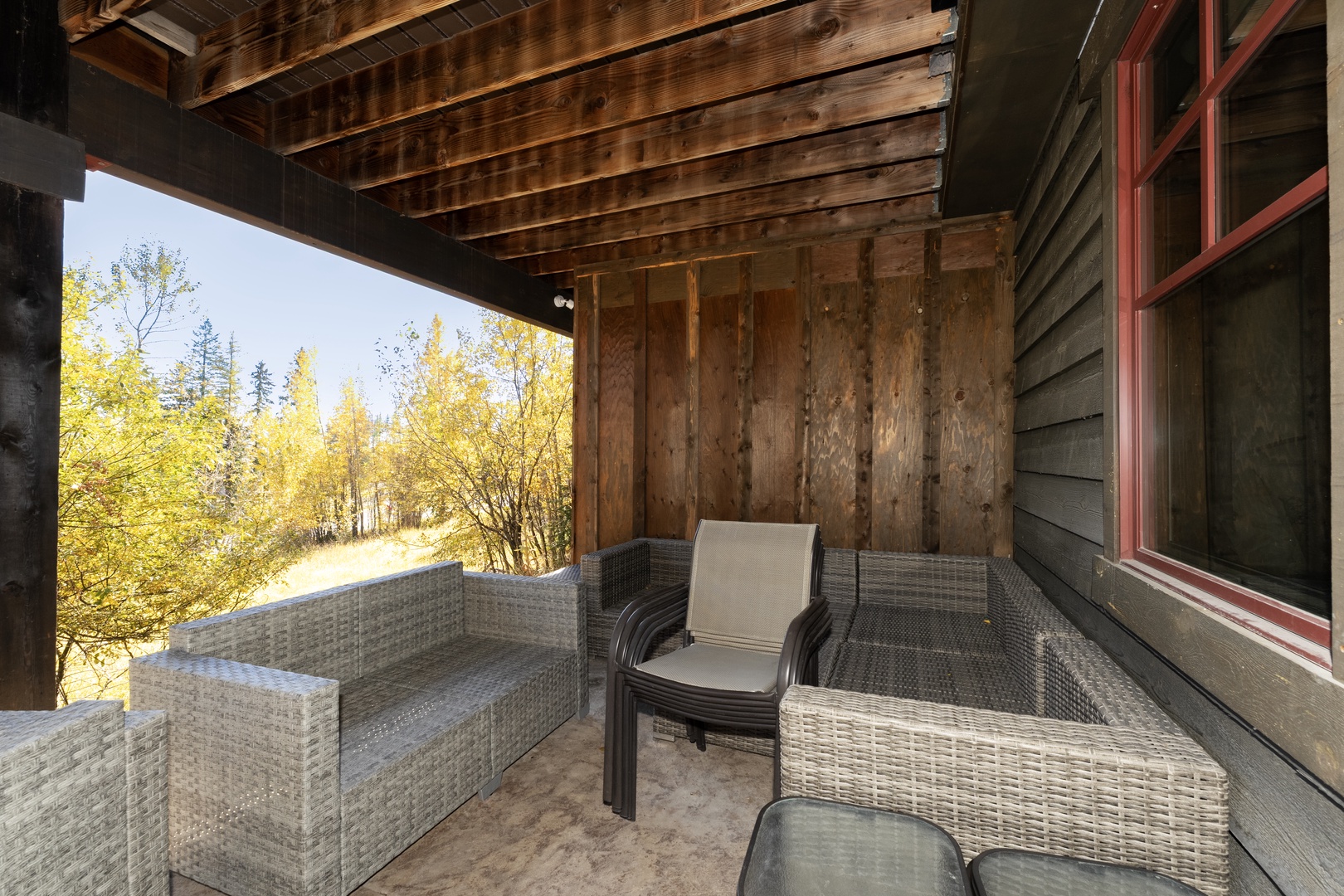 Settle into your private covered patio with comfortable wicker seating, where golden aspens frame peaceful views and warm wood accents create a cozy mountain retreat.