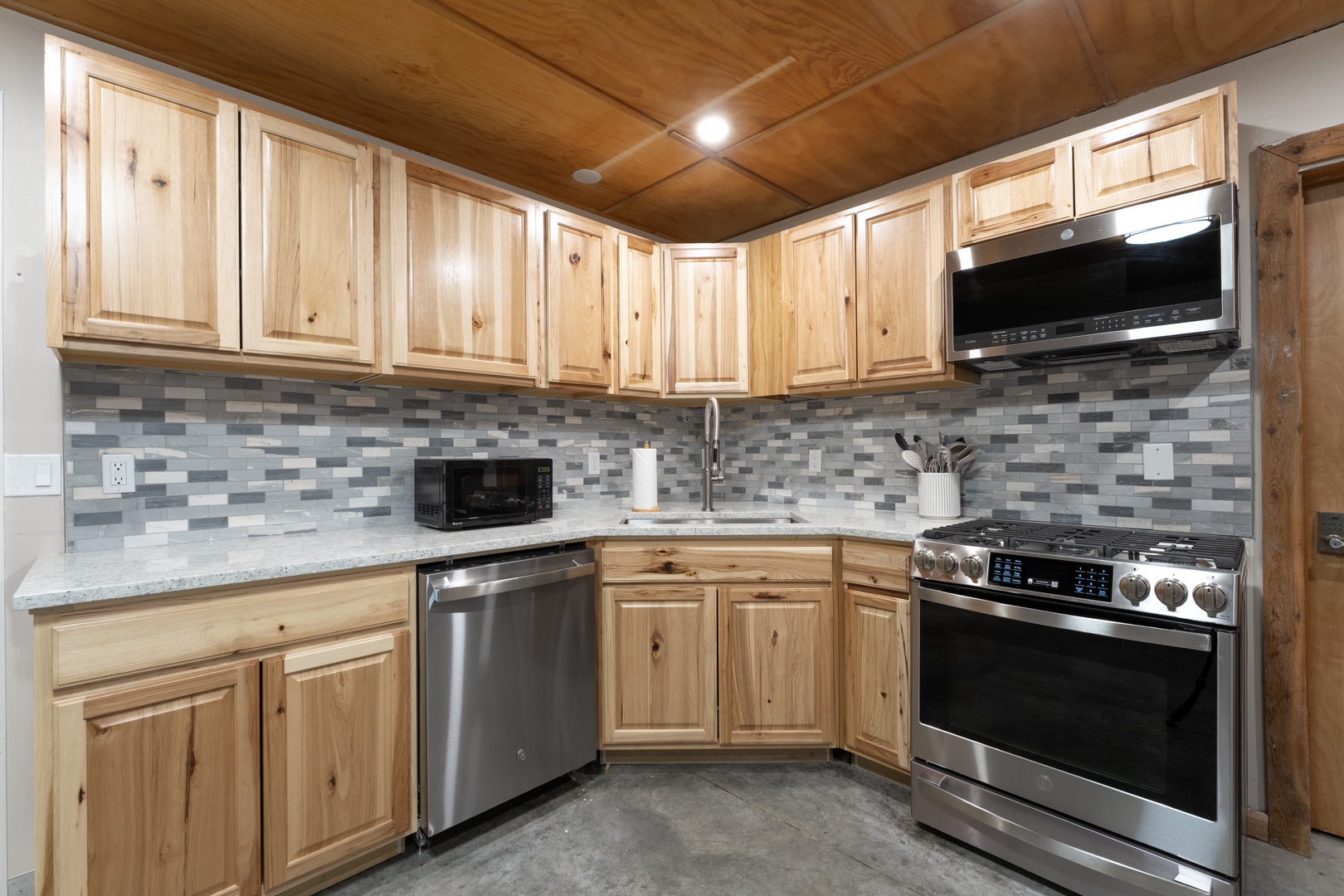 Cook your favorite meals in this fully equipped kitchen featuring stainless steel appliances, granite countertops, and warm wood cabinetry. Modern conveniences meet rustic charm in this welcoming space.