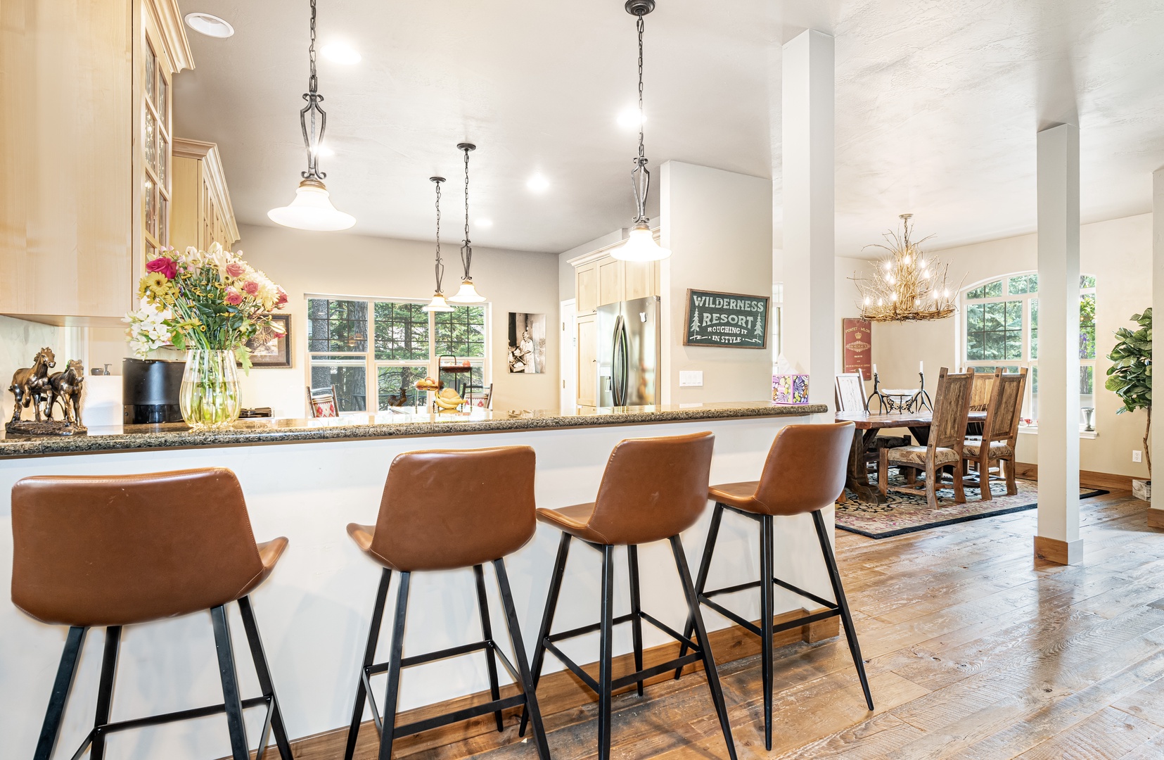 Spacious kitchen island with bar seating, fresh flowers, and elegant pendant lighting. The open layout flows into the dining area, creating a warm, inviting space for gathering.