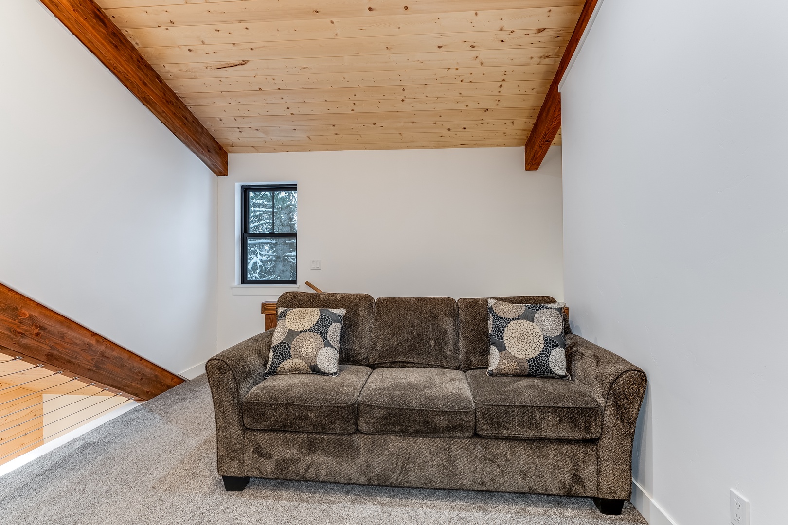 Relax under rustic wood beams in your cozy living space, where plush seating and natural light create the perfect retreat.