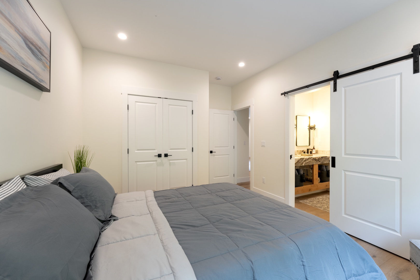 Sink into plush bedding in your private retreat. A charming barn door reveals the en-suite bath, while ample closet space keeps your belongings organized. Soft lighting and calming tones help you unwind completely.