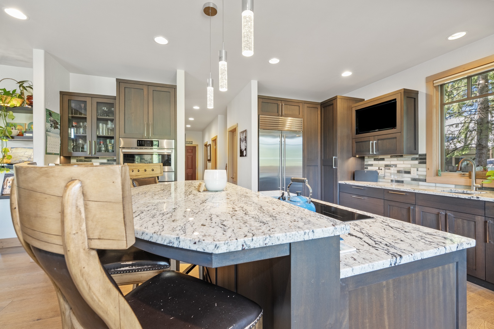 Your gourmet kitchen awaits—gorgeous granite countertops, sleek stainless appliances, and custom cabinetry make meal prep a pleasure. Gather at the island and enjoy forest views through expansive windows.