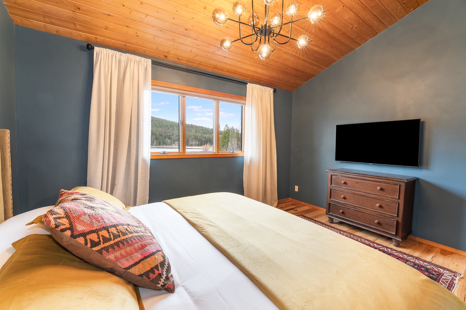 Drift off peacefully in this cozy bedroom, where warm wood ceilings and mountain views create your perfect alpine retreat.