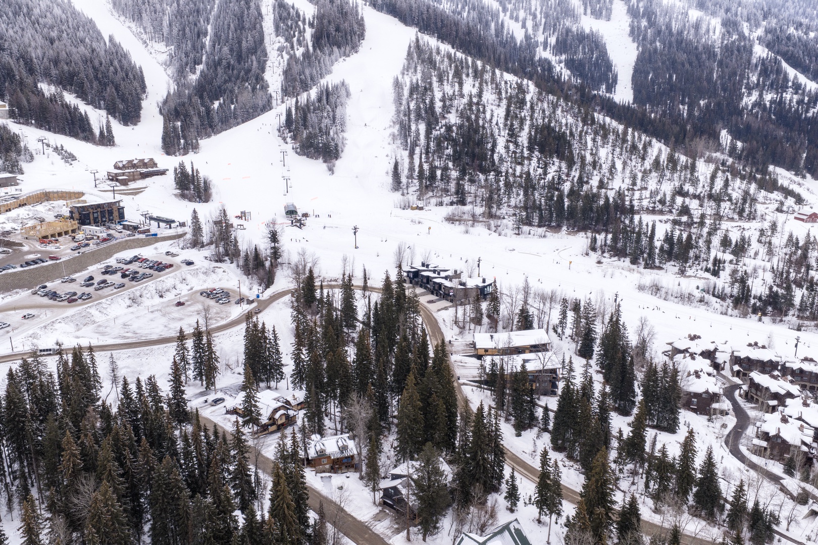 Aerial view of a pristine ski resort nestled in snow-covered mountains with groomed slopes and winter forest.