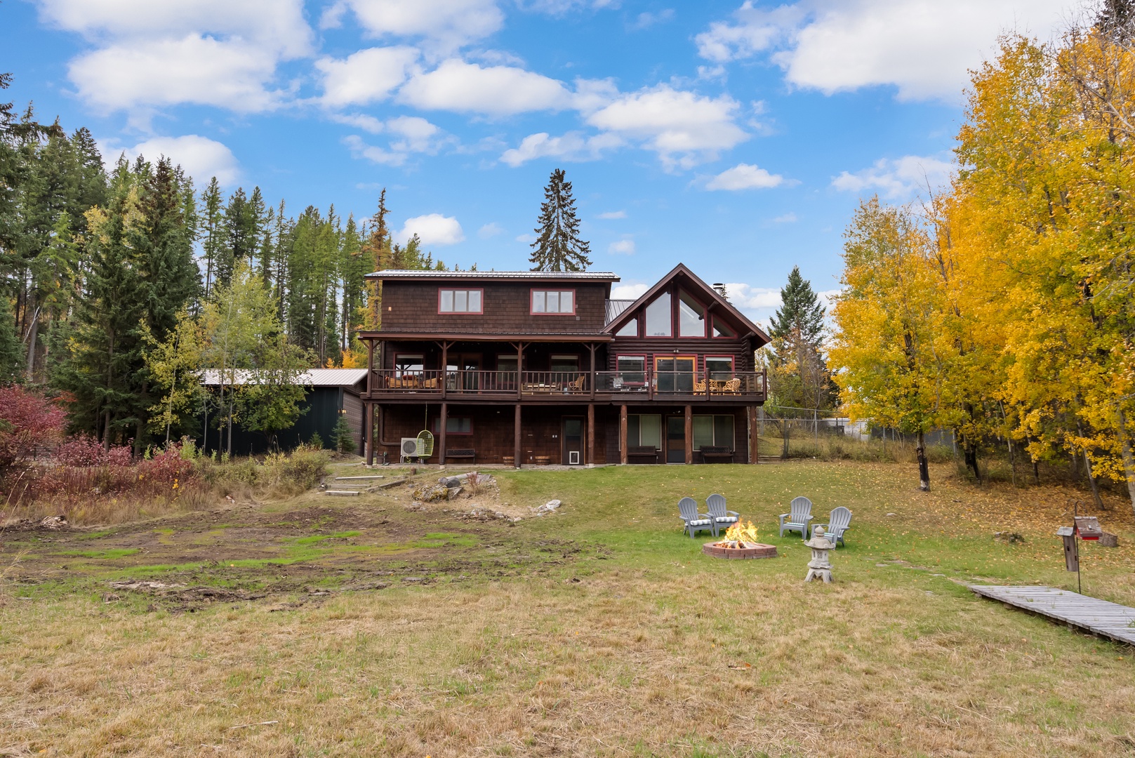 Rustic log cabin retreat nestled among vibrant autumn foliage with spacious outdoor grounds and fire pit for cozy evenings.