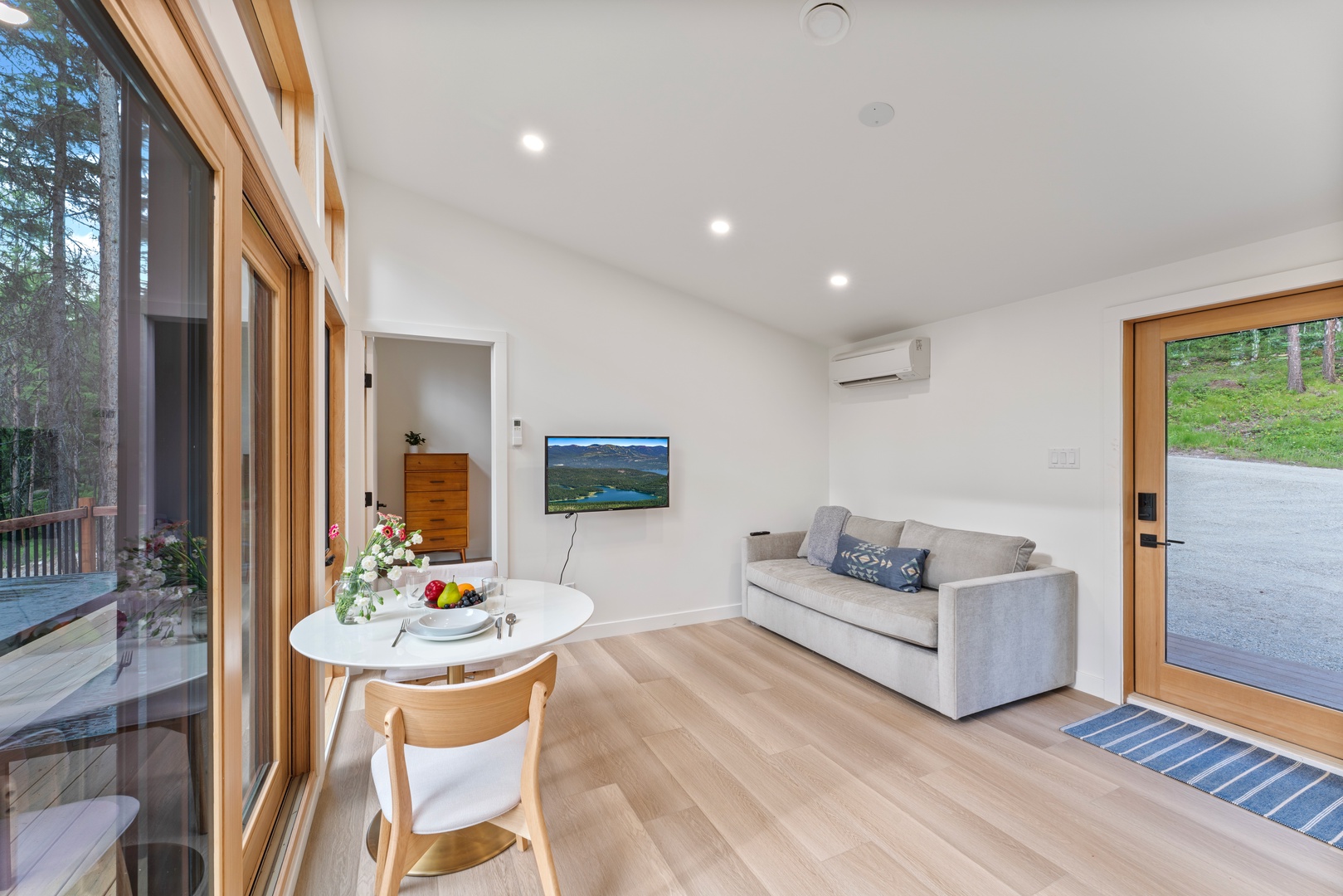 Unwind in your bright, modern living space with cozy seating and forest views streaming through floor-to-ceiling windows.