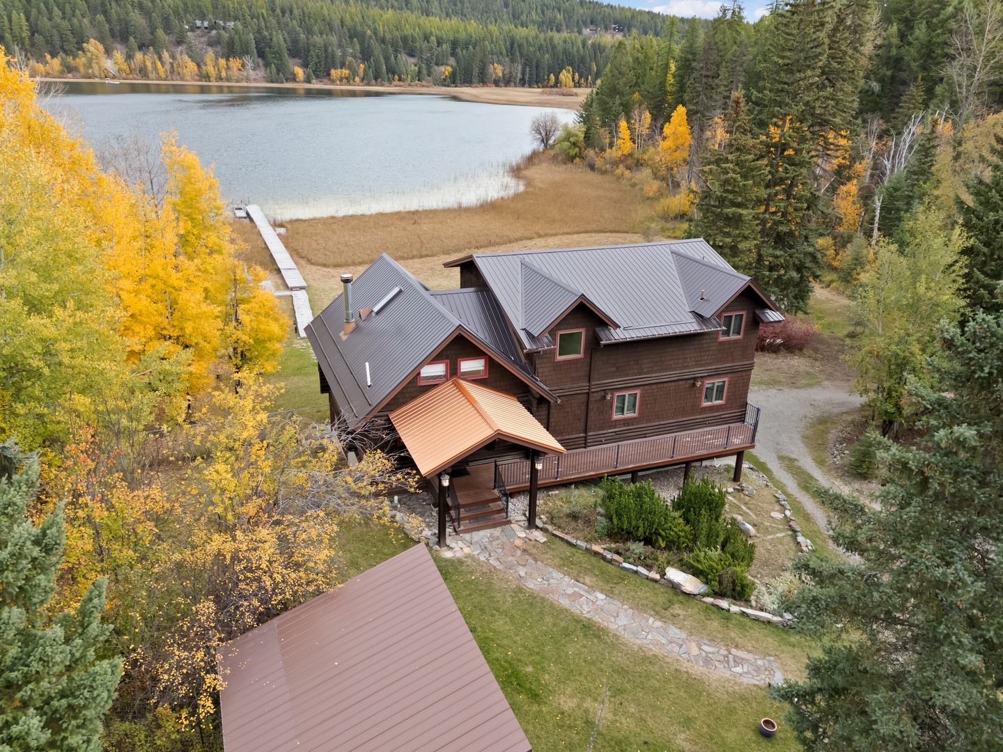 Stunning lakefront property nestled among vibrant autumn foliage with private dock access and mountain views.