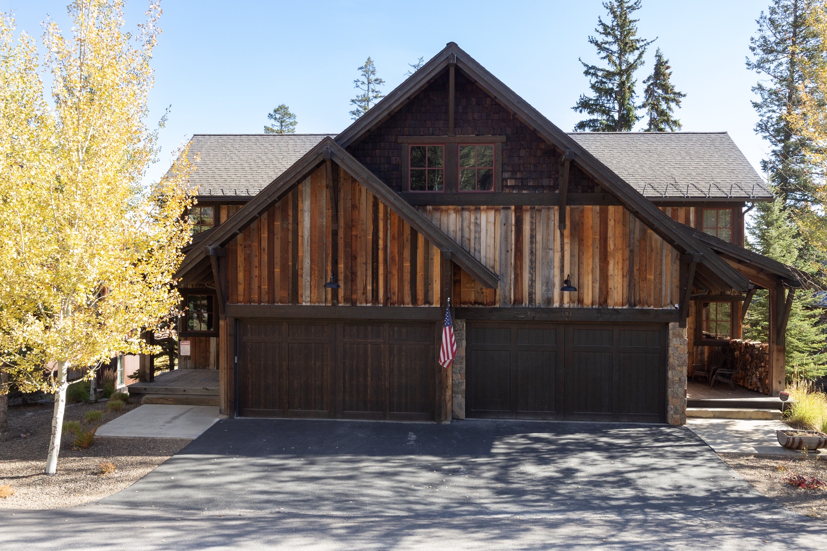 A charming mountain lodge nestled among aspens and evergreens, with rustic wood siding and stone accents creating an authentic alpine retreat with ample parking space.