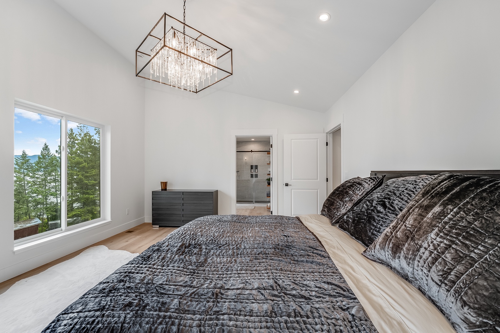 Wake up in your serene bedroom retreat with vaulted ceilings and stunning treetop views. Luxurious bedding and elegant lighting create the perfect escape for restful nights.