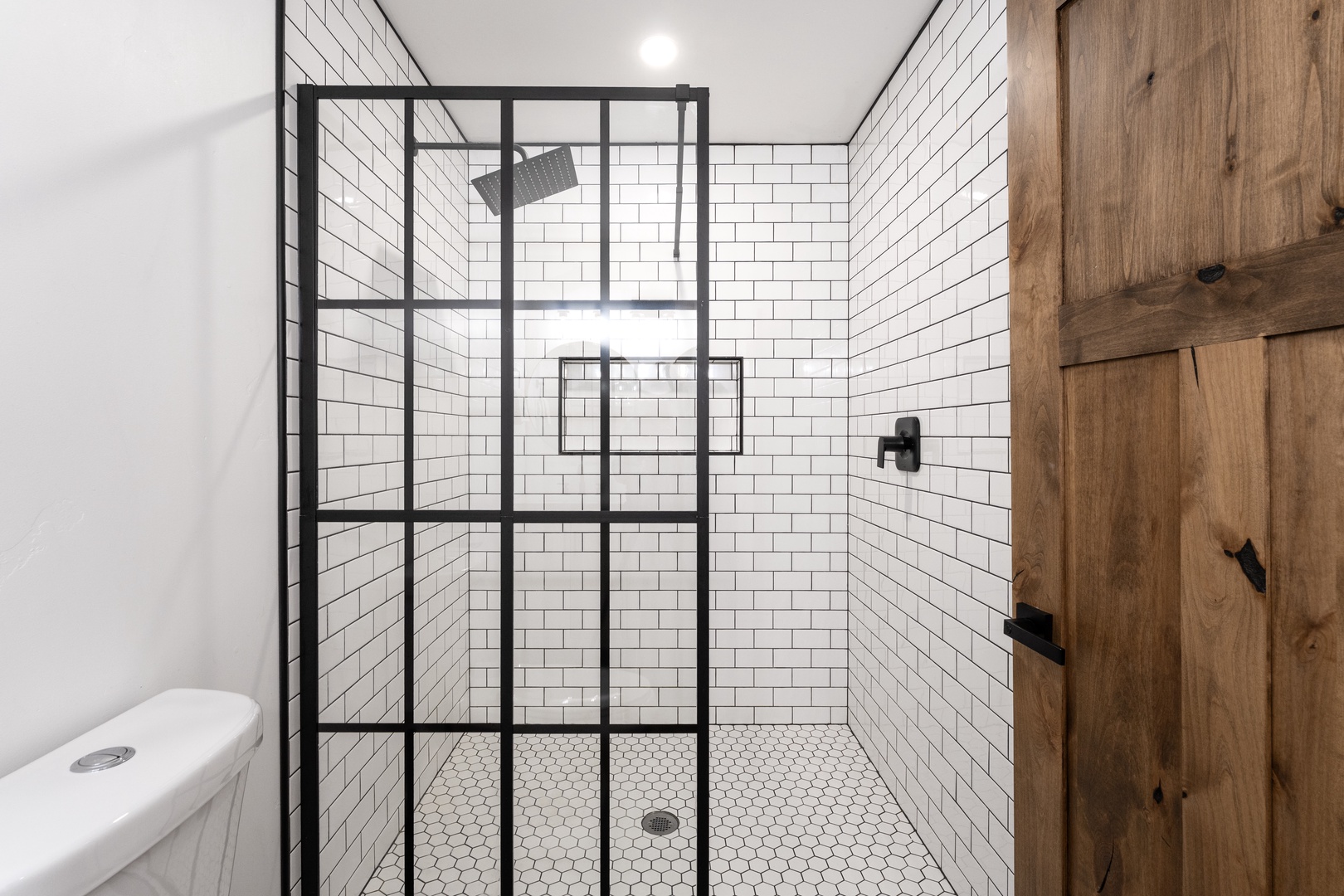 Step into your stylish bathroom featuring a sleek black-framed glass shower with classic white subway tiles and modern fixtures.
