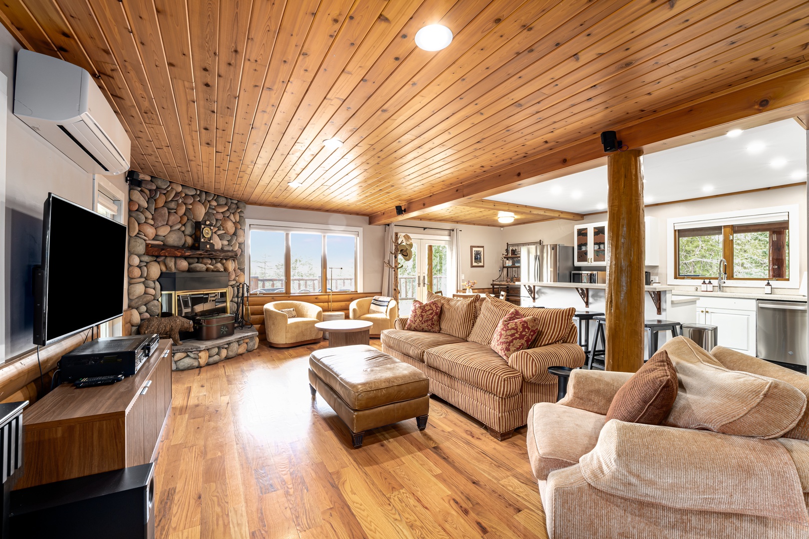 Settle into this warm, open living area where wood ceilings and a stone fireplace create a cozy mountain escape. You'll love relaxing on plush seating while enjoying your favorite shows.